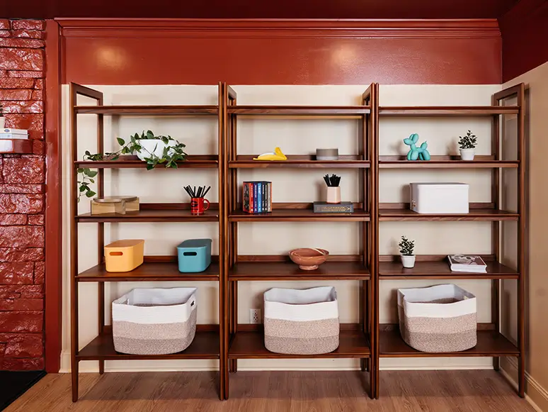 Wood shelving with storage baskets against a red brick wall