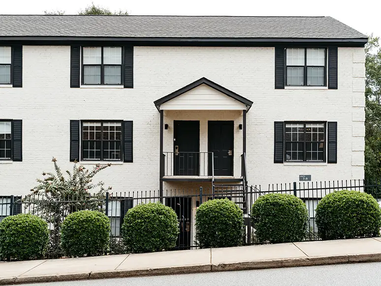White apartment building with black shutters and landscaping