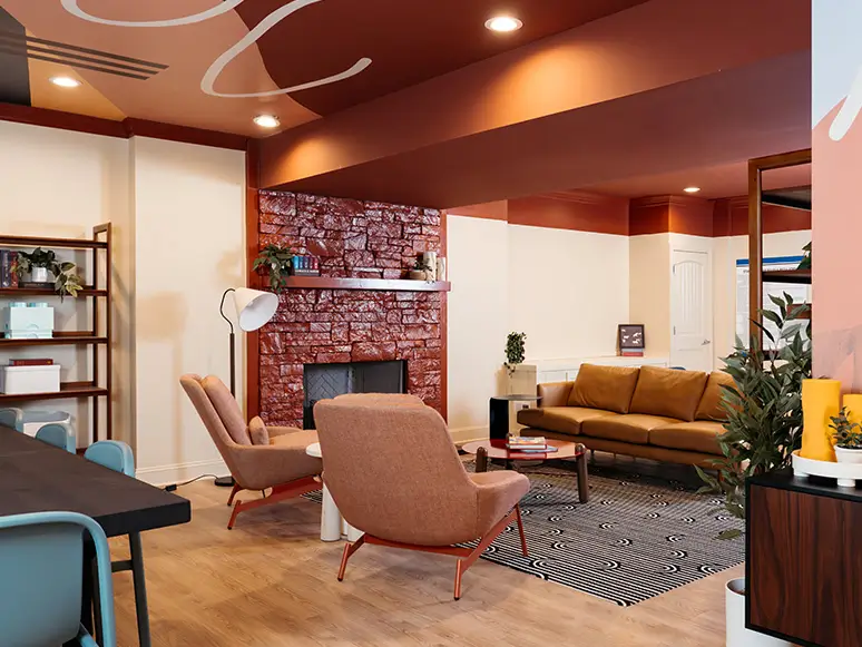 Lounge with leather sofas, pink armchairs, and a brick fireplace
