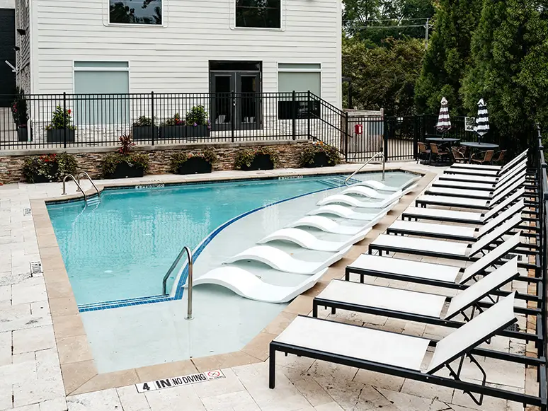 Pool with rows of white lounge chairs and a black fence