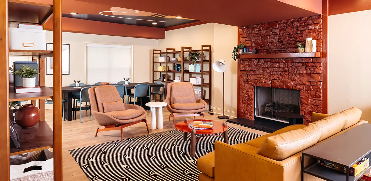 Lounge with leather sofas, pink armchairs, and a brick fireplace
