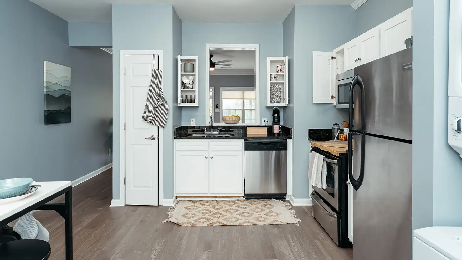 Open apartment kitchen with track lighting and stacked washer and dryer