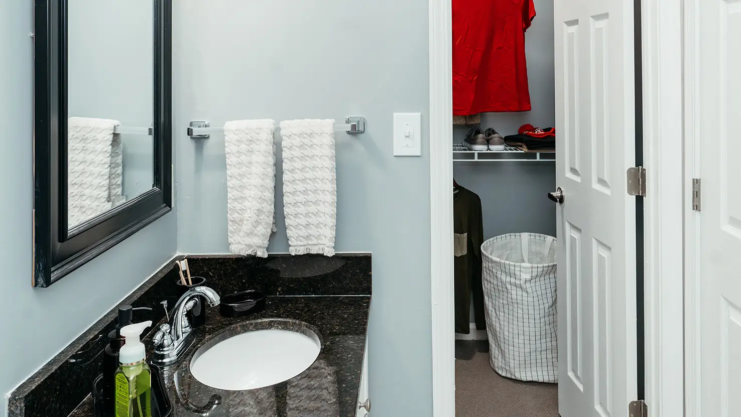 Apartment bathroom vanity with a view into a closet
