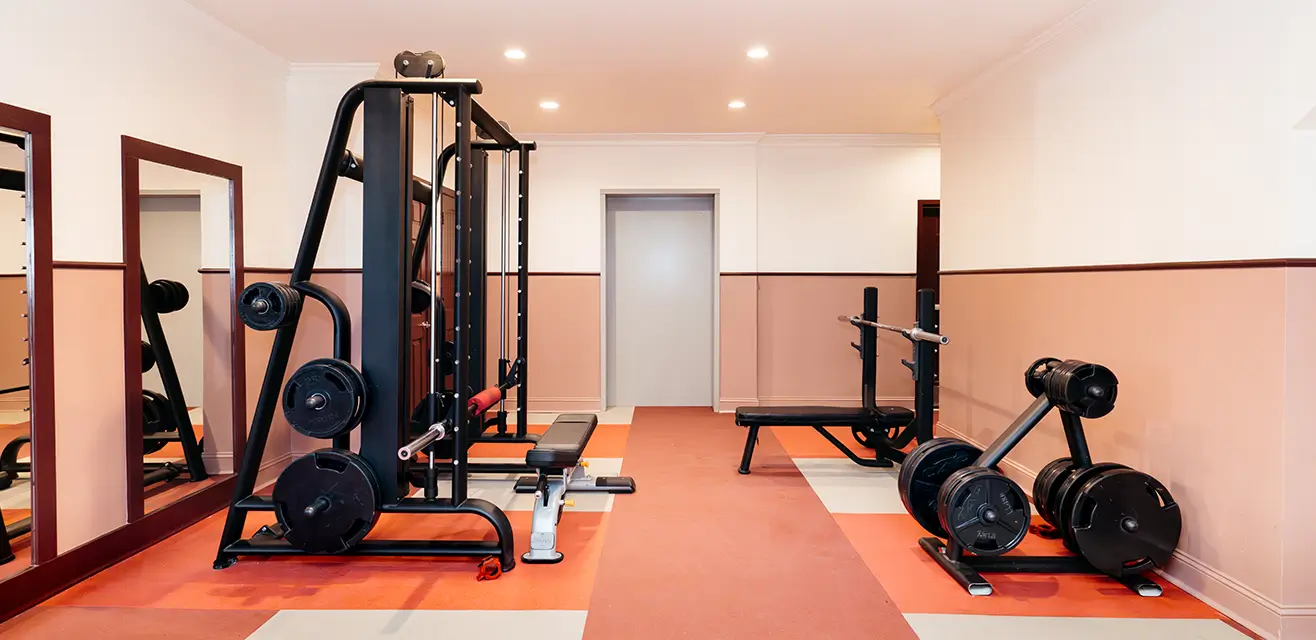 Fitness center with strength machines, dumbbells, and coral flooring
