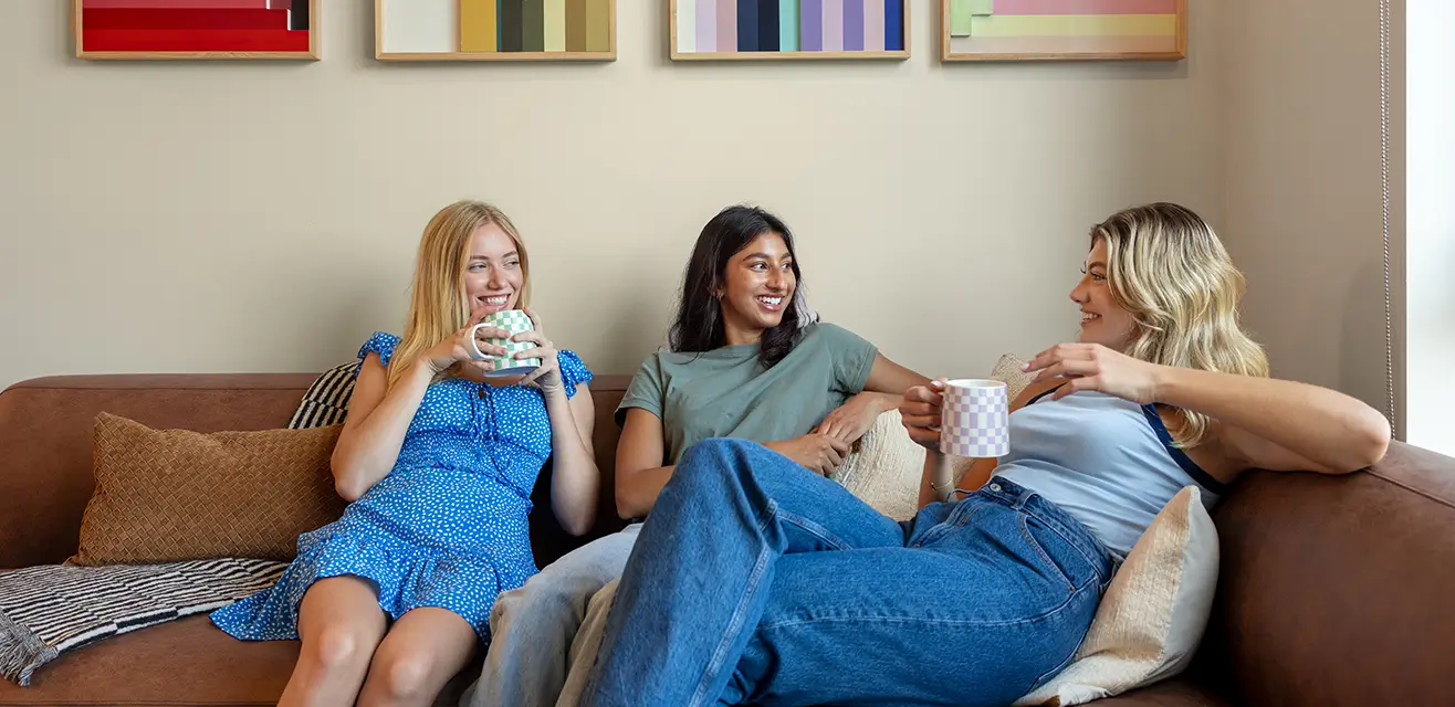 Three friends laughing together on a sofa