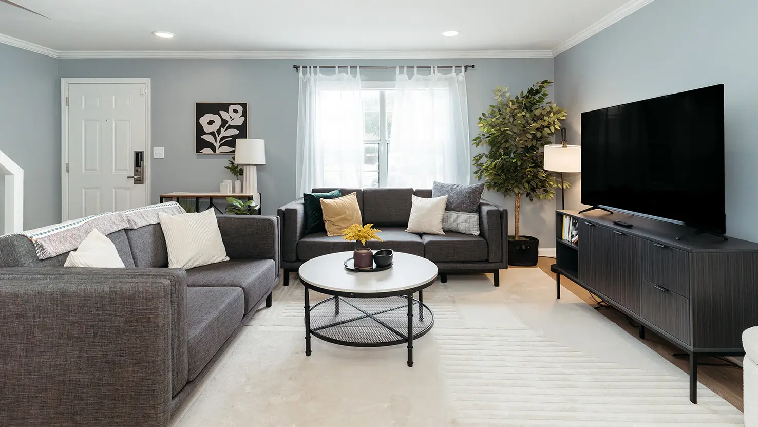 Furnished living room with a gray sectional sofa and wall-mounted TV