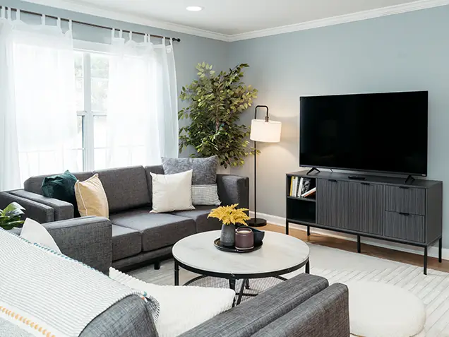 Furnished living room with a gray sectional sofa and wall-mounted TV