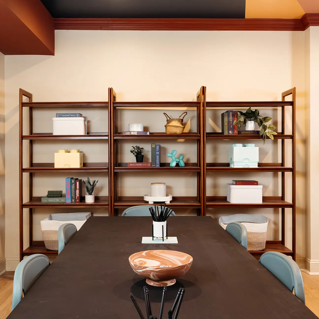 Study table with blue chairs in front of wood shelving