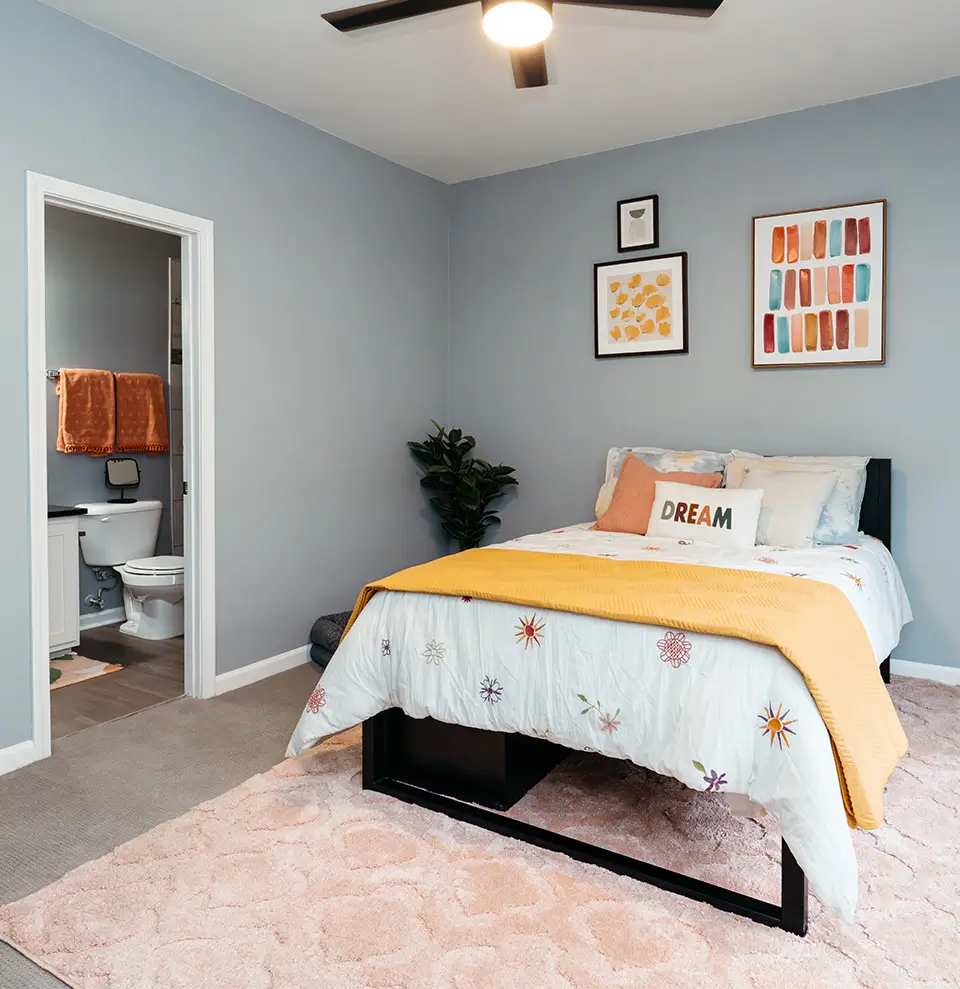 Furnished bedroom with yellow bedding and colorful wall art