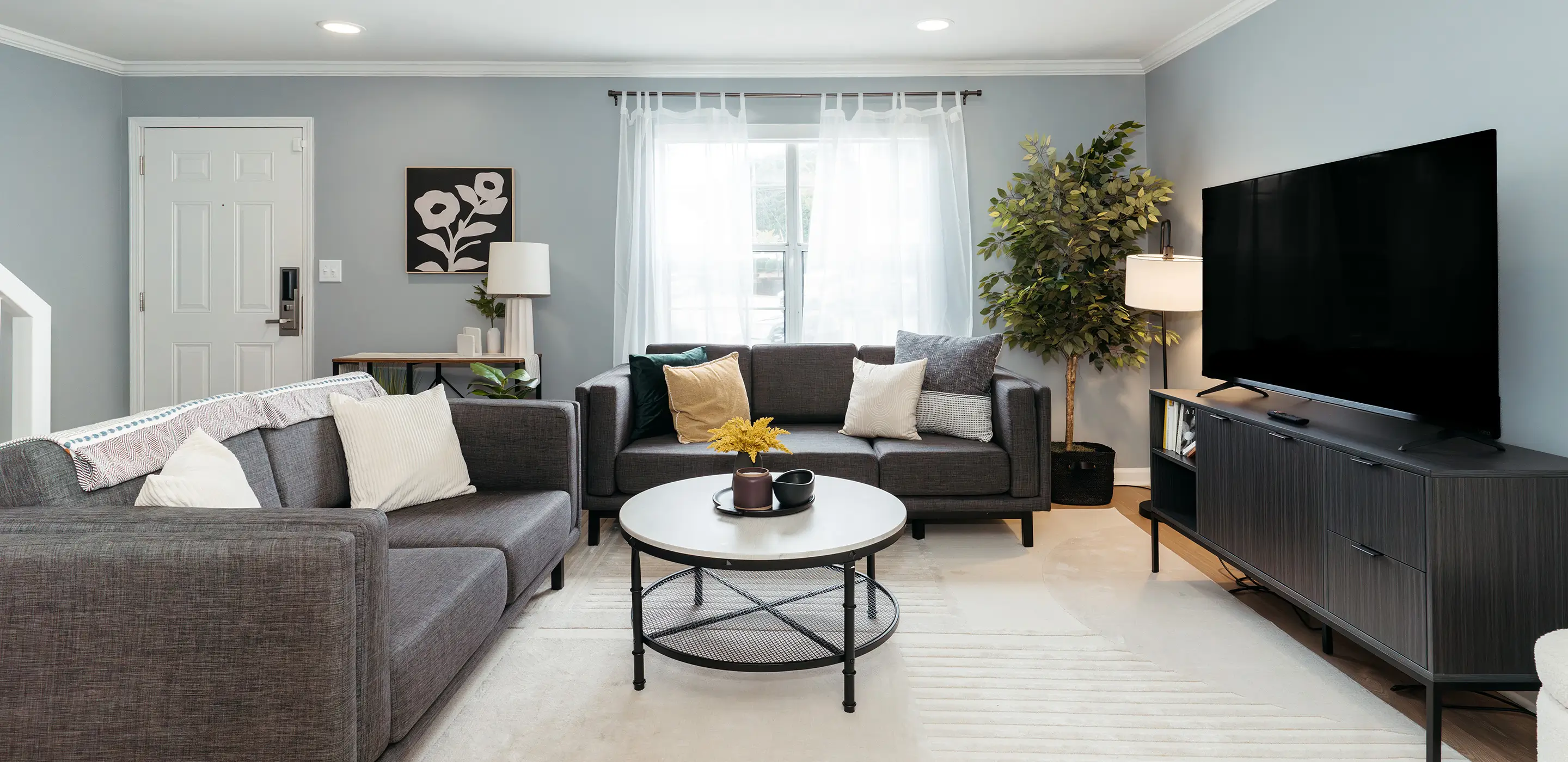 Furnished living room with a gray sectional sofa and wall-mounted TV