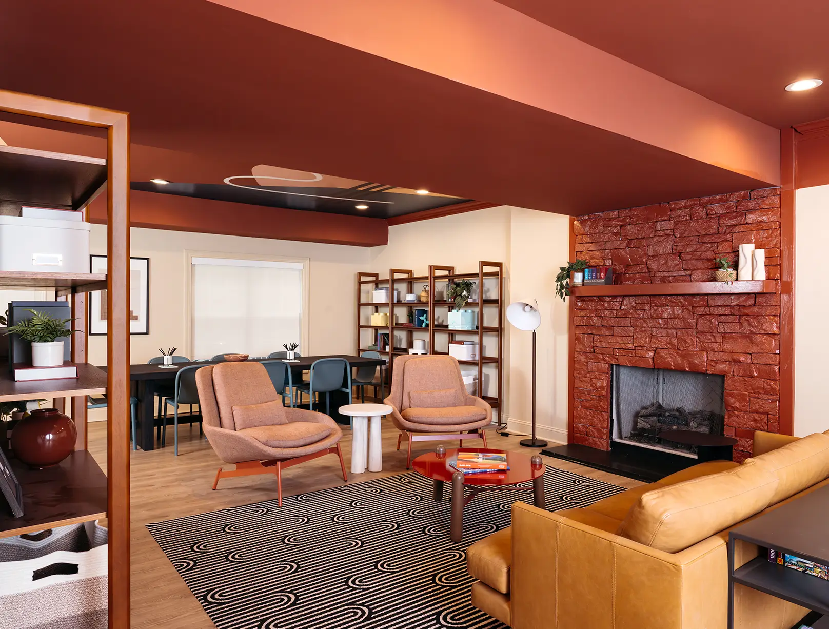 Lounge with leather sofas, pink armchairs, and a brick fireplace