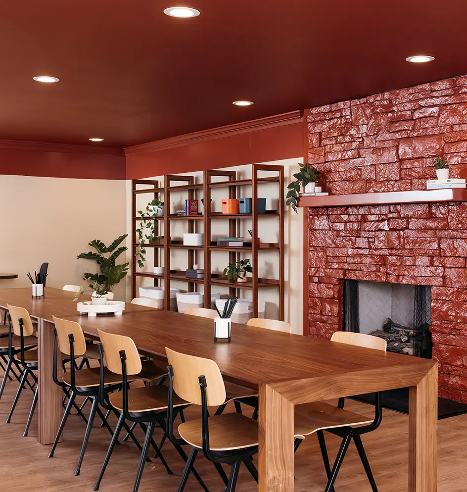 Study lounge with a long table, wood shelving, and a brick fireplace